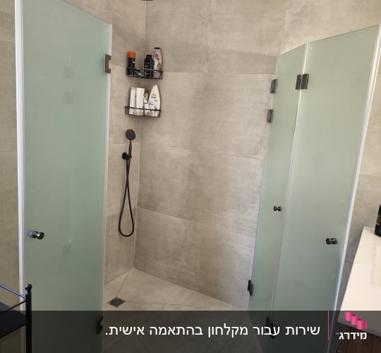 מקלחת עם דלתות זכוכית, ראש מקלחת ומדף עם מוצרים